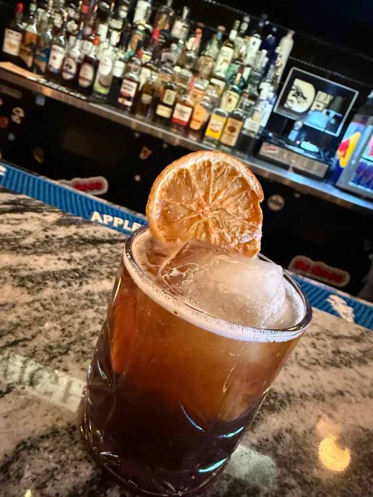 Amber cocktail with a charred citrus garnish at the Dragon Pit bar